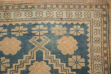 Close-up of a vintage Oushak's worn texture with sky blue floral and geometric patterns.