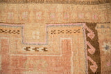 Hand-knotted texture and geometric hook-and-latch motifs on a distressed vintage rug.