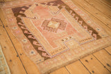 Angled view of a distressed Kars rug highlighting its pink and brown geometric prayer design.