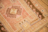 Close-up of a distressed Kars rug corner showing the knotty texture of its pink and brown geometric patterns.