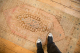 A personal perspective of a distressed Oushak rug with stepped geometric patterns in faded blush and bronze.