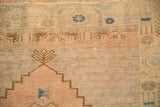 Detail of the distressed Oushak rug's worn pile, showing its stepped designs and blossom finials.