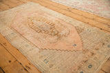 Angled view of a vintage Oushak rug featuring a stepped medallion with dusty rose and bronze colors.