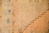 Low-pile texture of a distressed Oushak showing stepped bronze patterns and slate blue floral motifs.
