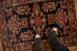 Personal perspective over the deep navy field and sprawling floral motifs of an antique Lilihan rug.