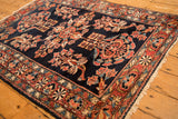 Angled view of the antique Lilihan rug's corner, highlighting the brick red floral border and navy field.