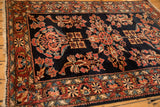 Angled view of an antique Lilihan rug's floral pinwheel border against its navy blue field.