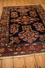 Angled shot highlighting the traditional floral borders and navy pile of an antique Lilihan rug.