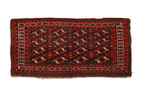 Antique Turkmen rug with repeating geometric guls in tomato red, navy blue, and ivory on a coffee brown field.