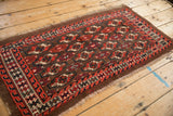 Rows of geometric guls in red and ivory on an antique Turkmen rug with frayed edges and even wear.