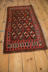 Angled view of an antique Turkmen rug showing repeating geometric guls on a coffee brown field.