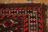 Worn corner of an antique Turkmen rug with a red, navy, and brown geometric wave border.