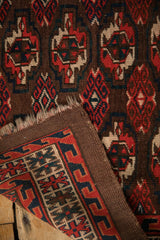 Corner of antique Turkmen rug showing worn pile, tattered end, and woven foundation.