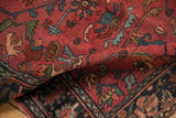 The flexible weave of an antique Lilihan rug, folded to show its raspberry red field and low pile texture.