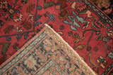 Folded corner of an antique Persian rug showing its hand-knotted back and raspberry red pile.