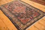 Angled view of a vintage Tajabad rug with an intricate navy, blush, and sky blue pattern.