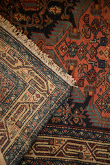 The folded corner of a vintage Persian rug reveals its blush pile and hand-knotted foundation.