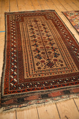 Angled perspective of an antique Belouch rug, showcasing its full length, prayer design, and low pile.