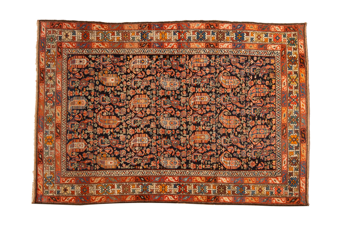 Antique Hamadan rug with intricate botehs and blossoms covering a navy blue field within colorful stylized borders.