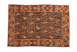 Antique Hamadan rug with intricate botehs and blossoms covering a navy blue field within colorful stylized borders.