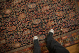 A detailed view of the staggered boteh motifs and sprawling blossoms on the navy blue field of an antique Hamadan rug.