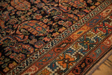 Intricate crab and serpent borders beside the navy field of a hand-knotted antique Hamadan rug.