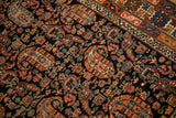 Angled detail of boteh motifs and crab border on a navy blue antique Persian Hamadan rug.