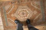 Distressed vintage Oushak rug with earthy tones, shown on the floor for scale.