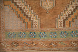 Detail of a vintage Oushak rug's stepped medallion and dusty jade green pinwheel starburst border.