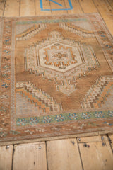 Angled view of a vintage Oushak rug, showing its stepped medallion and distressed low-pile texture.