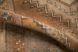 Textured low pile of a distressed Oushak rug with geometric designs in coffee brown, sand, and dusty turquoise.