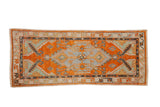 Vintage distressed Oushak rug runner with a geometric medallion in burnt orange, slate blue, and jade green.