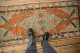 A look down at the distressed Oushak runner's medallion design in burnt orange and slate blue.