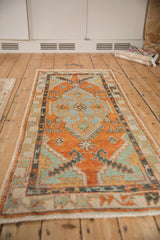 Vintage distressed Oushak runner viewed at an angle, highlighting its elongated orange and blue medallion.