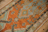 Detailed shot of the distressed hand-knotted pile with orange and jade green floral renderings.