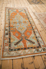 Angled perspective of a vintage distressed Oushak runner with bold orange and slate blue medallions.