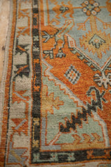 Close-up of the Oushak rug's charcoal border, with visible knot heads and burnt orange pile.