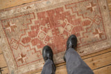 Distressed Oushak rug showing worn pile, geometric patterns, and faded colors under boots.