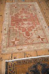 Distressed Oushak rug showing pinwheel corner, narrow vine border, and soft fringe.