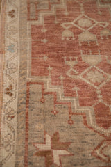 Distressed vintage Oushak rug detail with dusty plum, beige, and blue geometric patterns.