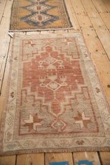Distressed Oushak rug corner showing pinwheel starburst and vine border in plum, ivory.