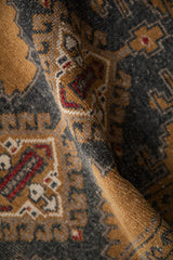 Soft fold showing the distressed, low pile texture of a vintage Turkish Oushak rug.