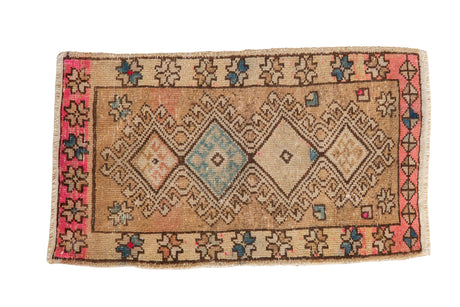 Vintage distressed Oushak rug mat with geometric diamond medallions in sand, pink, and powder blue.
