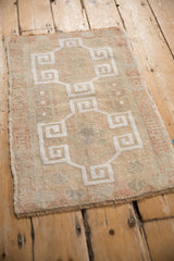 Distressed Oushak rug detail, white geometric meander pattern on muted sandalwood and terra cotta.