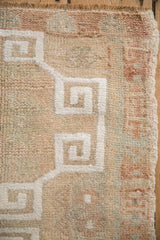 Distressed Oushak rug texture highlighting white geometric pattern against muted ivory and terra cotta.