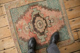 Corner of distressed Oushak rug showing pale cantaloupe, denim blue, and ivory pile.