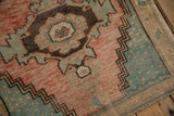 Vintage Oushak rug close-up: distressed cantaloupe field, denim blue spandrel, and zigzag border.
