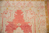 Low-pile texture and faded cherry red blossom motifs on a distressed vintage Oushak rug.