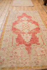 Perspective view of a distressed Oushak rug with its faded red medallion and saffron border.