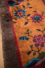 Corner detail of a vintage Art Deco rug showing the floral pile, dark border, and original selvage.
